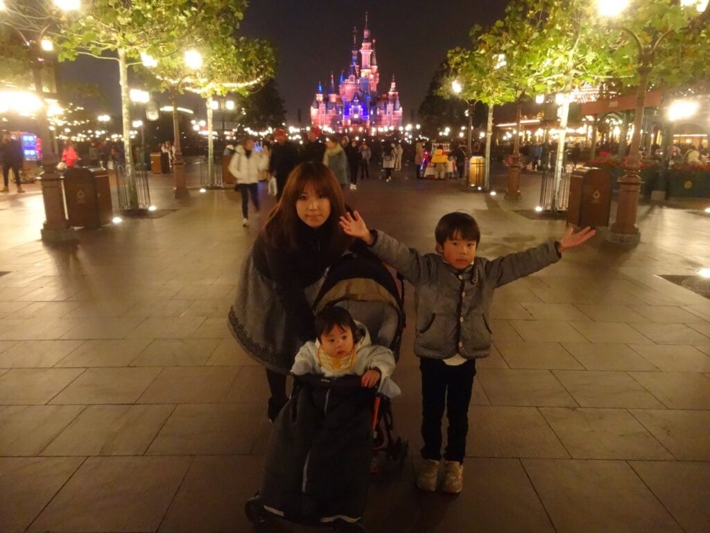 夜の上海ディズニーランドでEnchanted Storybook Castleを背景にした家族