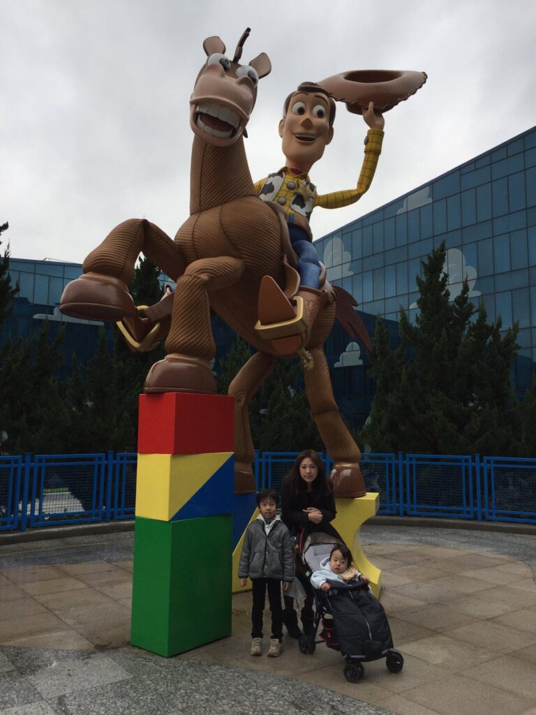 上海ディズニーランドのウッディとブルズアイの像を背景にした家族